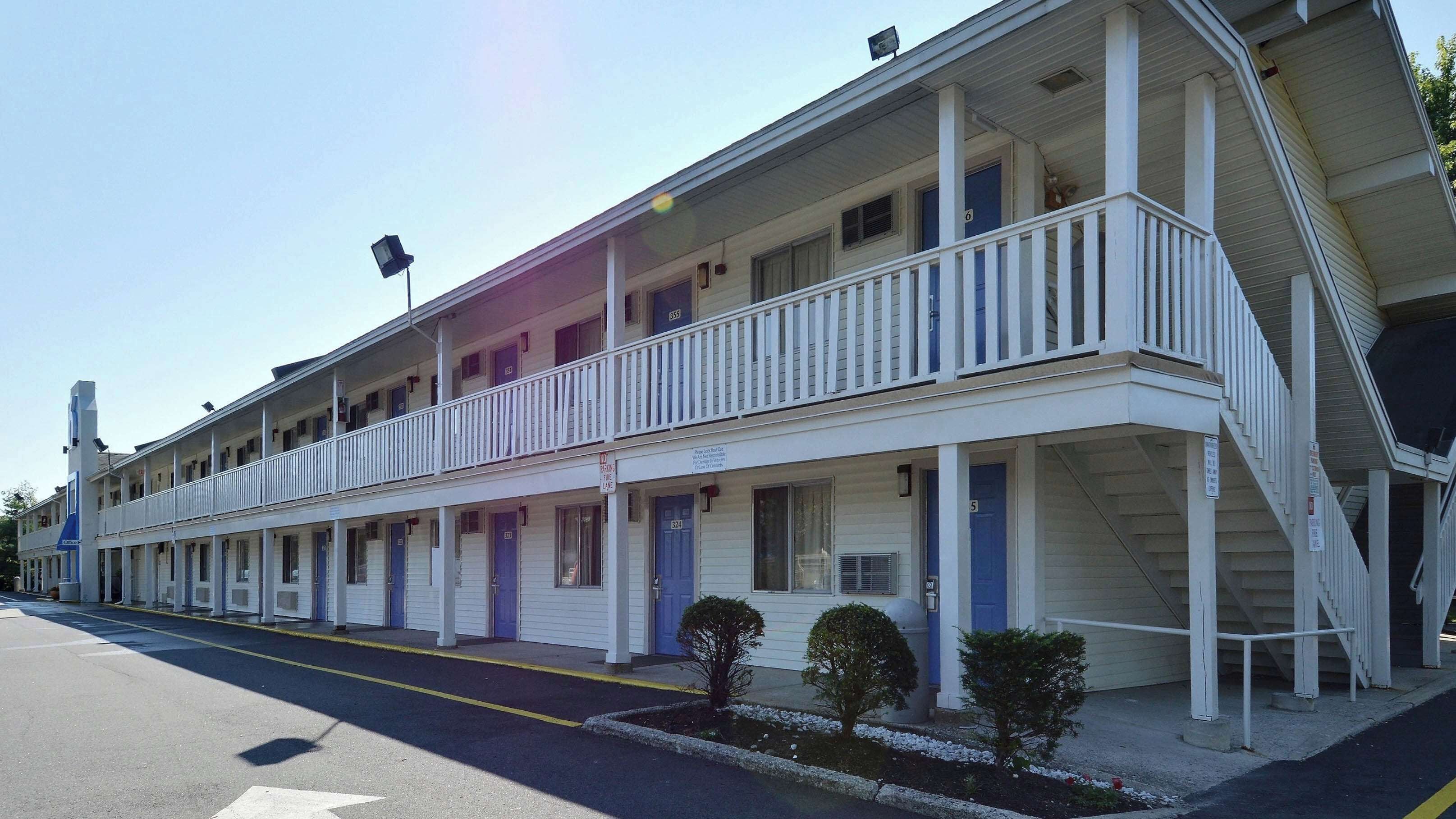 A motel with a two-story structure, a covered front porch, and a parking lot.
