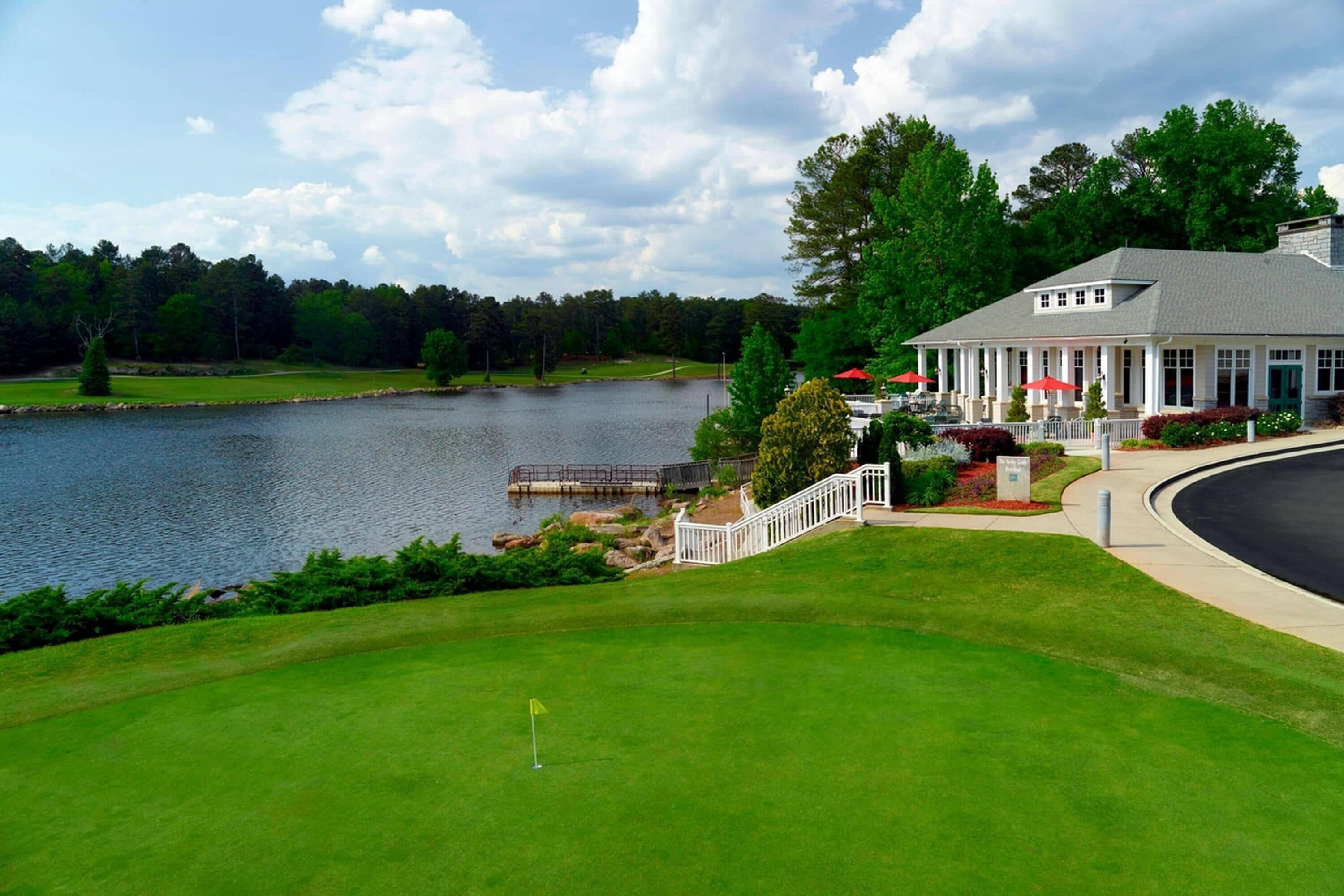 Un parcours de golf doté d’un club-house, d’un lac et d’une pelouse bien entretenue.