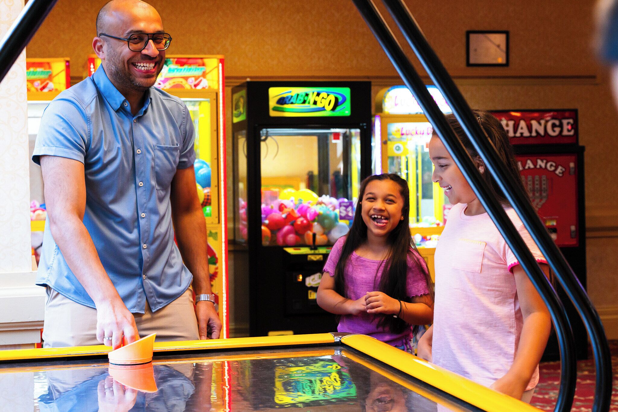 Een man en twee kinderen spelen een spelletje in een speelhal op een kermis.