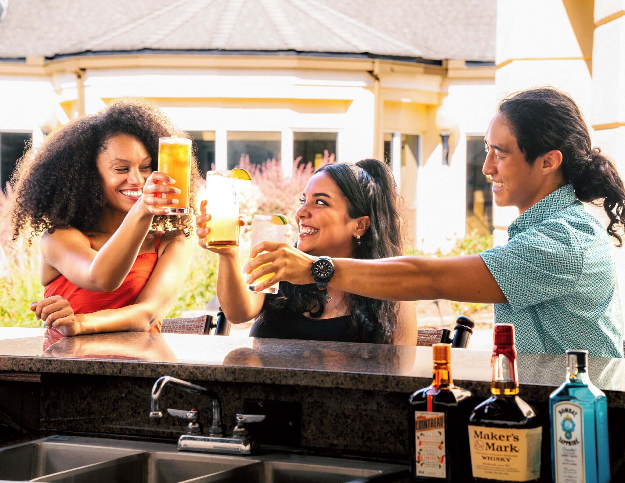 A bar area with a countertop, a sink, and bottles of liquor.