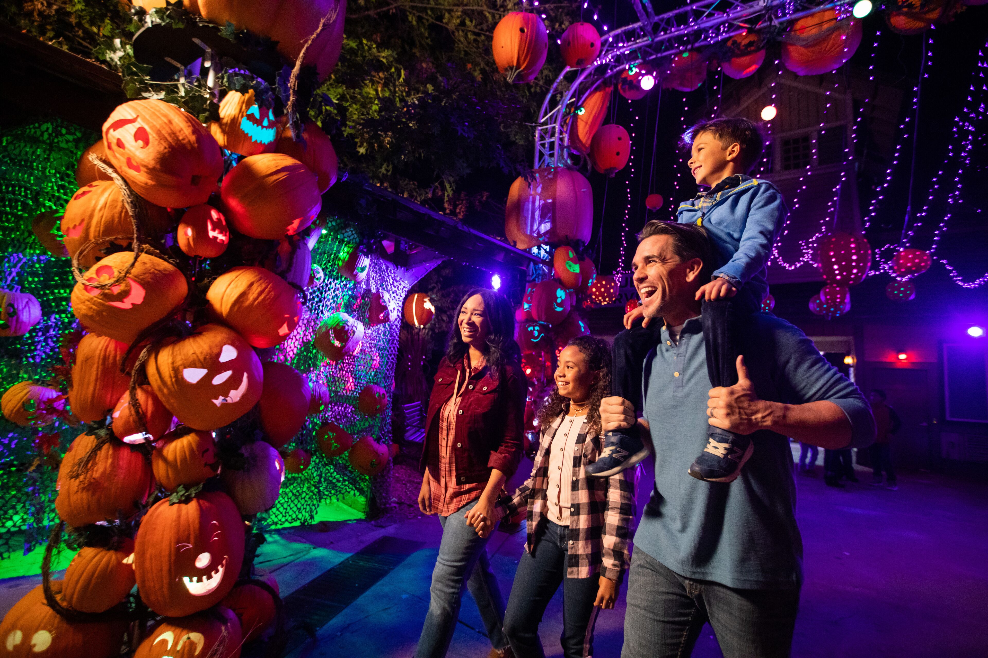 Un grupo de personas en un evento con temática de Halloween, con calabazas iluminadas y decoraciones.