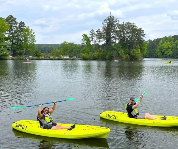 Two kayaks on a calm lake with trees in the background.