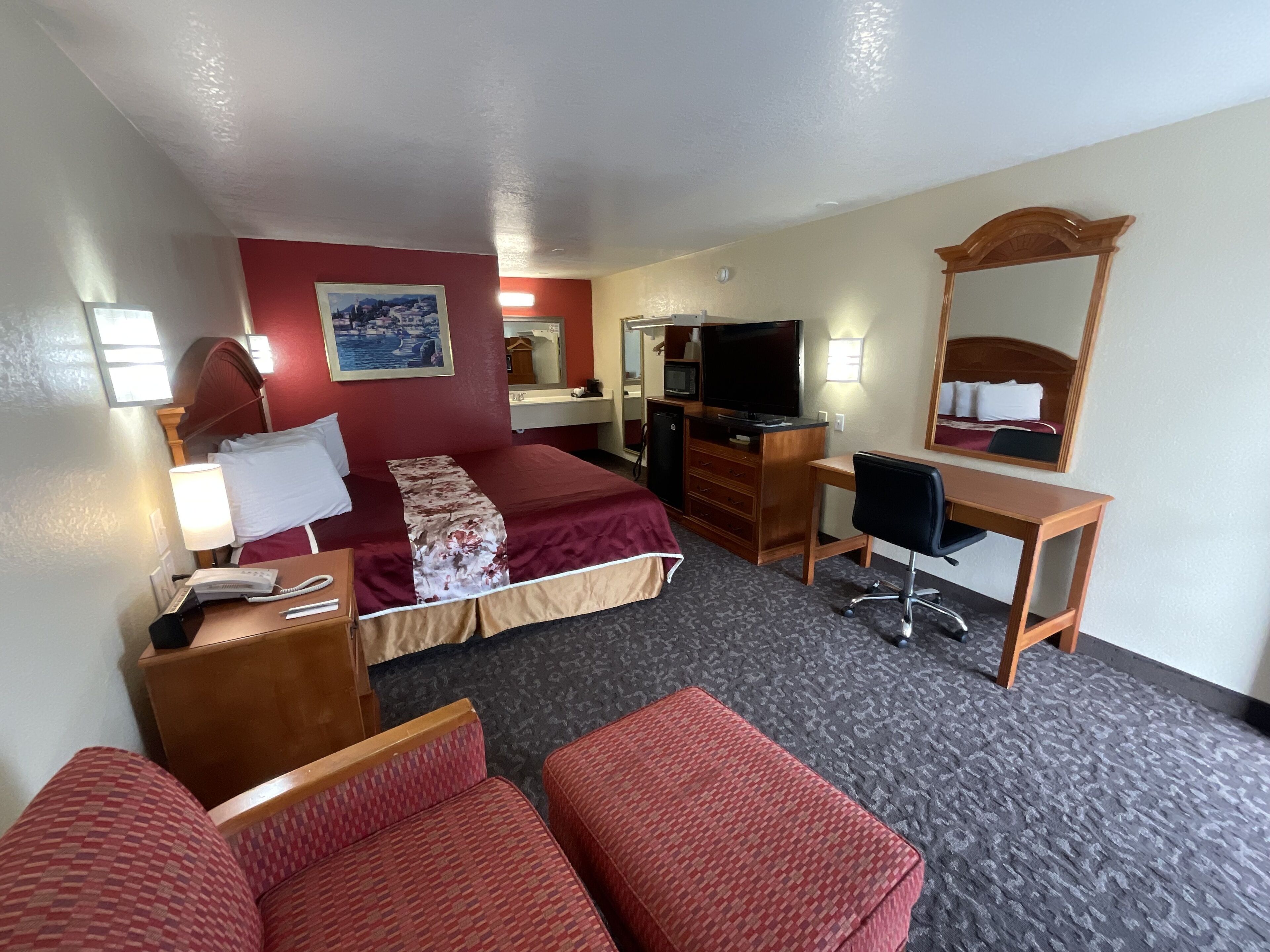 A hotel room with a bed, desk, chair, and a television.