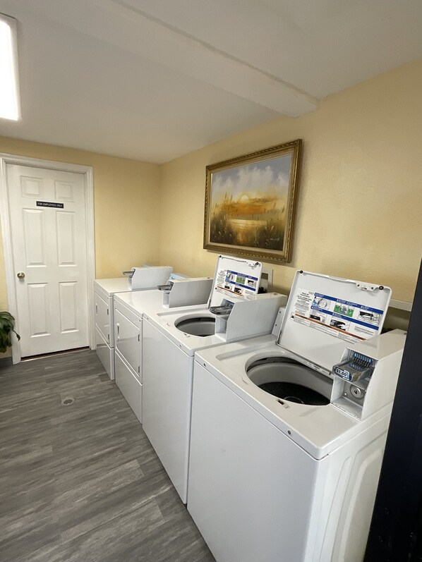 A laundry room with two front-loading washing machines, a dryer, and a door labeled "For Employees Only". - Knights Inn Punta Gorda (Punta Gorda)