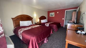 A hotel room with two beds, a desk, a mirror, and a telephone.