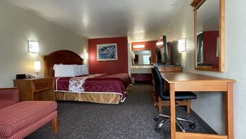 Una habitación de hotel con cama, escritorio, silla y un espejo grande.