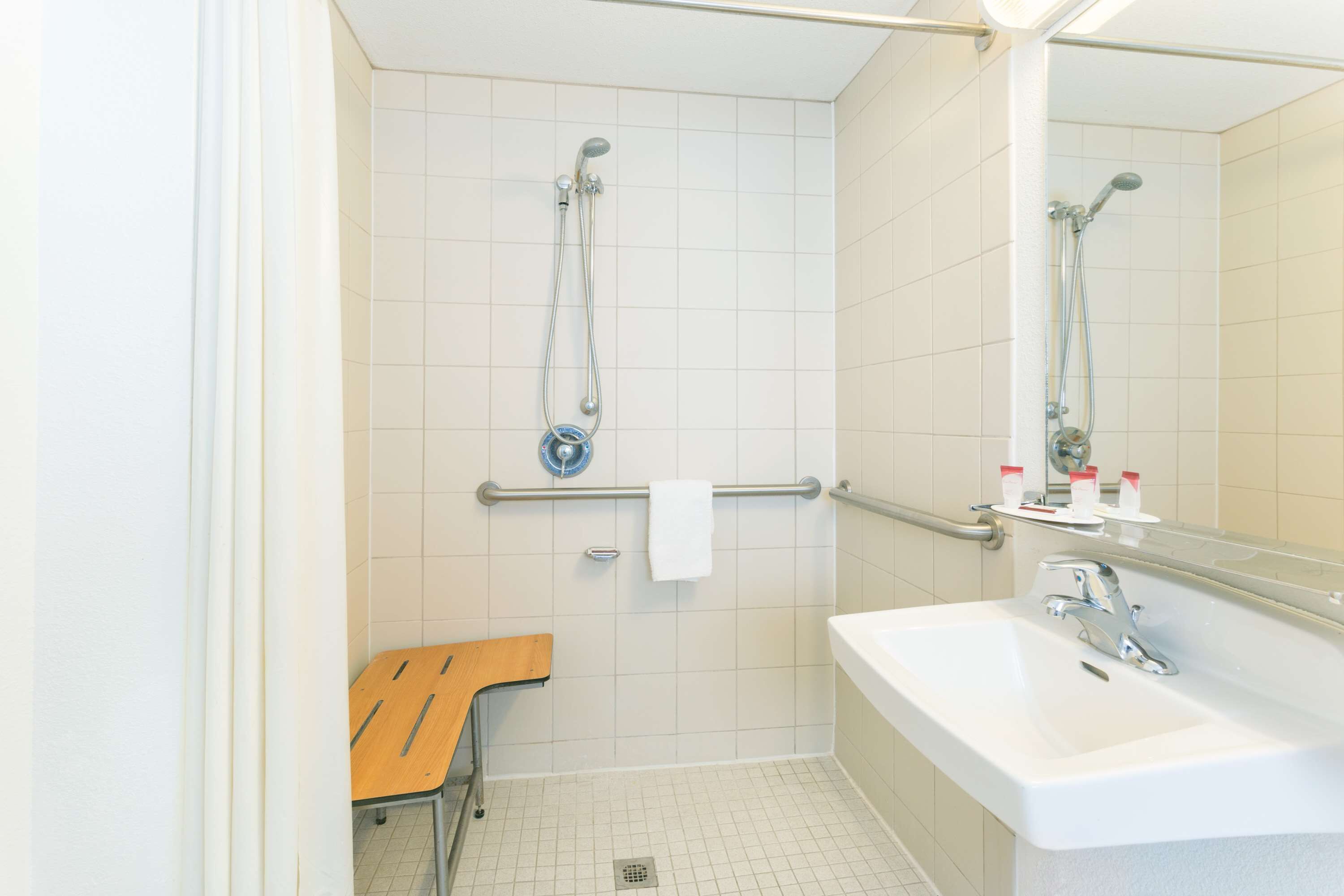 A bathroom with a shower, a sink, and a mirror.