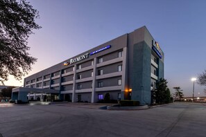 A multi-story hotel with a prominent 'Baymont' sign, featuring a modern architectural design with a flat roof and a large entrance area. - Baymont by Wyndham Arlington At Six Flags Dr (Arlington)