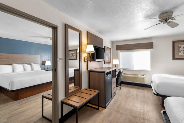 Una habitación de hotel con cama, escritorio, silla y un espejo grande.