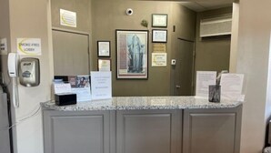 Un área de recepción con cartel de no fumar, teléfono, certificados enmarcados y carteles informativos.