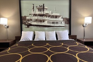 A hotel room with a bed, two bedside tables, and a large framed picture of a steamboat on the wall. - Super 8 by Wyndham Alton (Alton)