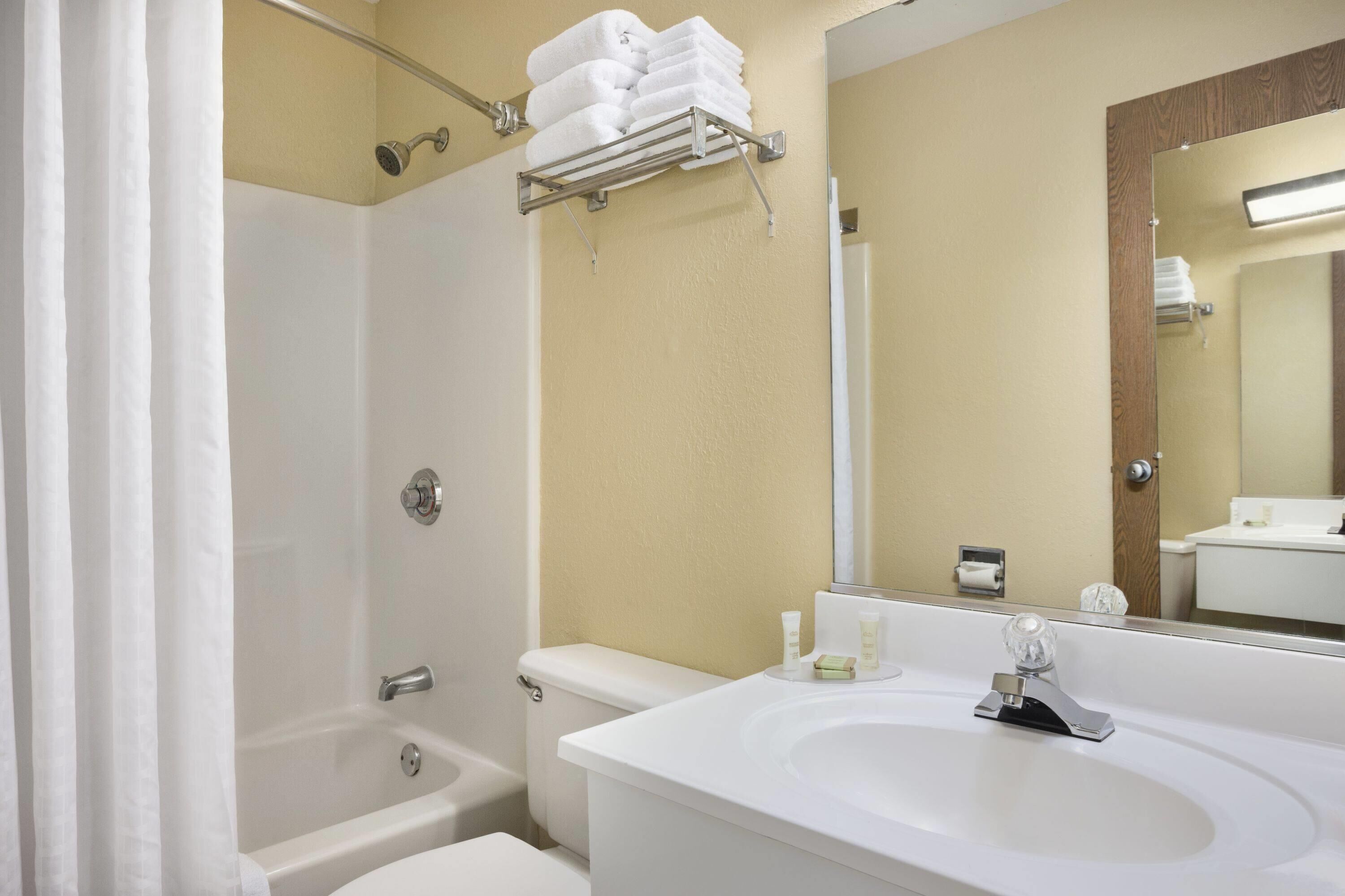 A bathroom with a bathtub, toilet, sink, and a towel rack with folded towels.