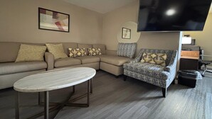 Una sala de estar con sofá modular, sillón estampado y una mesa de centro redonda.