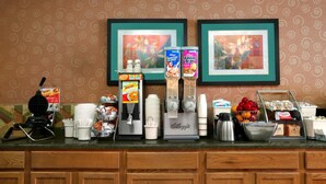 A breakfast bar with a waffle maker, coffee station, and various food items. - Super 8 by Wyndham Peoria East (East Peoria)