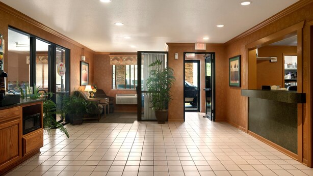 A spacious lobby with a reception desk, a seating area, and a large potted plant. - Super 8 by Wyndham Peoria East (East Peoria)