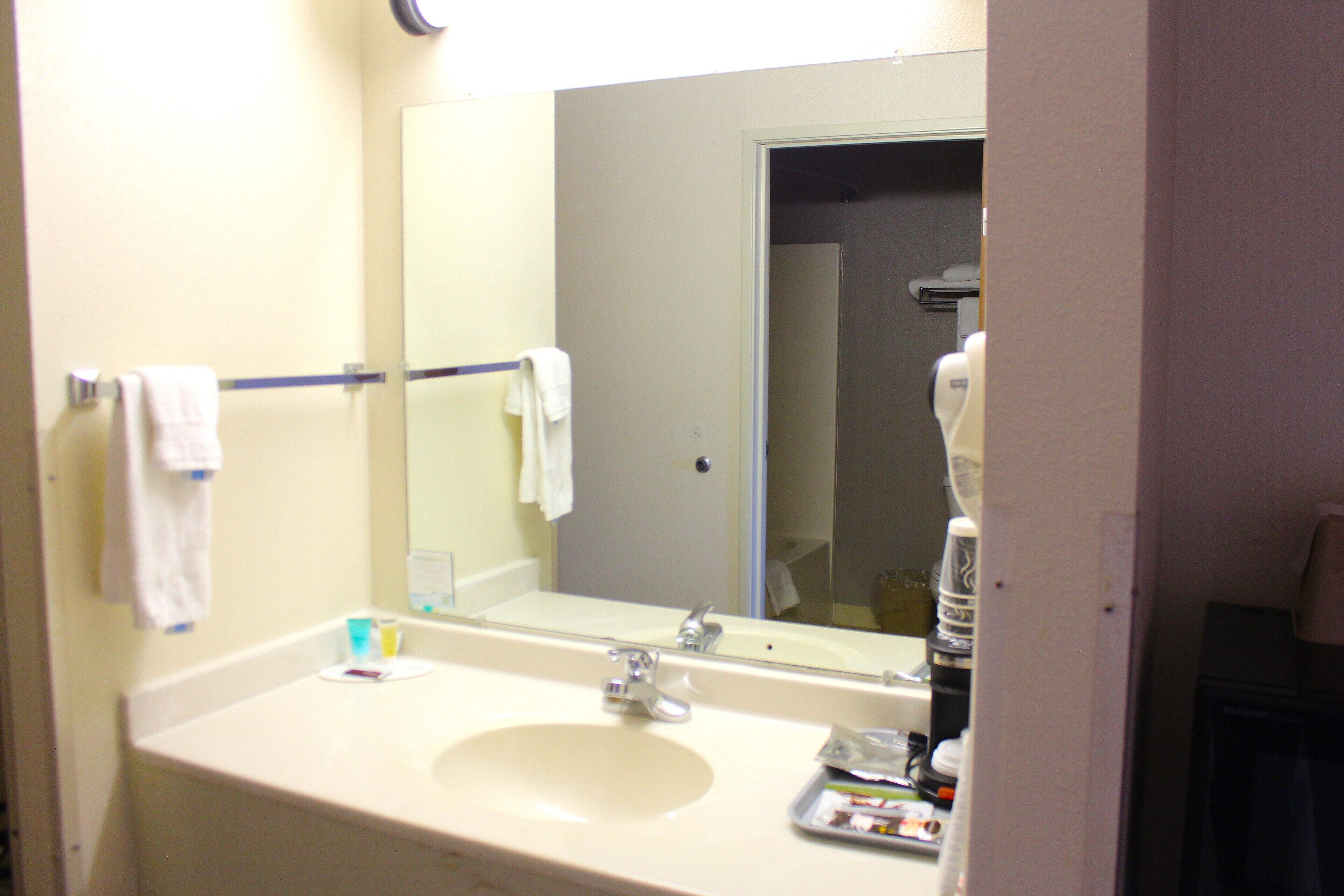 A bathroom with a sink, mirror, and towel rack.