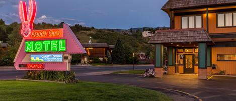 A motel with a neon sign advertising 'Rabbit Ears Motel' and 'Quality Lodging at Affordable Rates'.