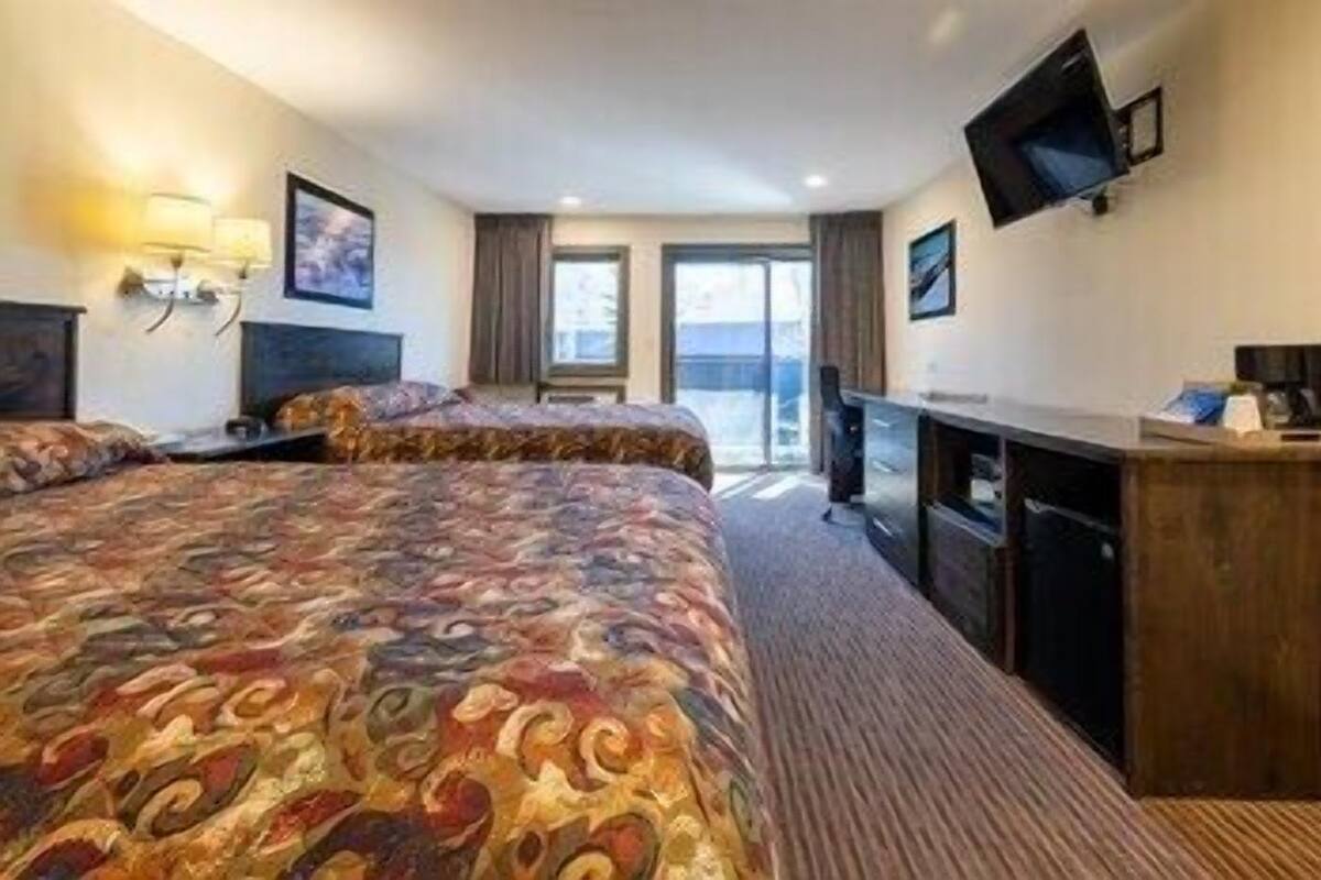 A hotel room with a large bed, a desk, a flat-screen TV, and a view of the outdoors.