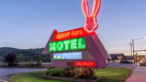 Letrero de motel iluminado con neón y un conejo como mascota, que indica disponibilidad.