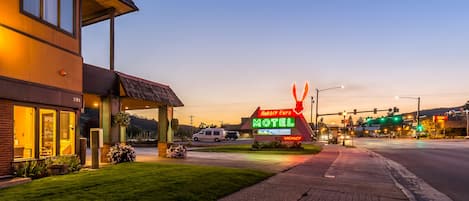 A motel with a neon sign, a grassy lawn, and a street view.