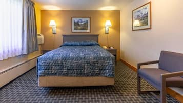 Ett hotellrum med en stor säng, två sänglampor, en stol och två inramade tavlor på väggen.