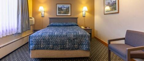 Una habitación de hotel con una cama grande, dos lámparas de noche, una silla y dos cuadros en la pared.