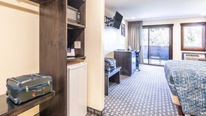 Habitación de hotel con cama, escritorio, silla y una maleta en un estante.