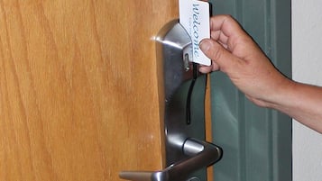A hand holding a 'Welcome' card next to a door handle.