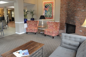 Un hall con chimenea de ladrillo, alfombra estampada y dos sillones.