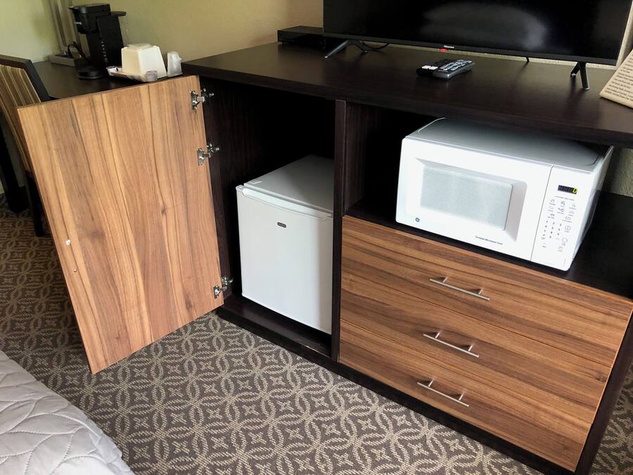 A compact kitchenette with a microwave, a small refrigerator, and a cabinet with drawers.