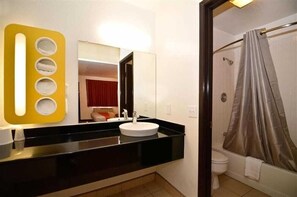 A bathroom with a black countertop, white sink, and a shower with a grey curtain.