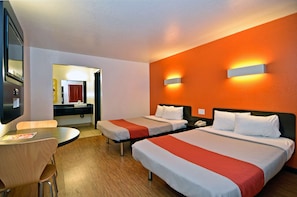 A hotel room with two beds, a desk, and a mirror.