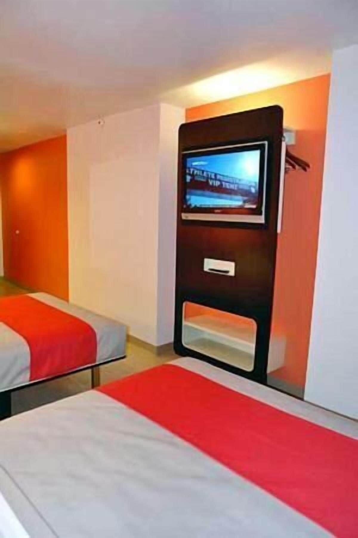 A hotel room with two beds, a TV mounted on the wall, and a red and white color scheme.