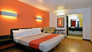 Ein Hotelzimmer mit Bett, Stuhl, Schreibtisch und einem durchgegangenen Tür sichtbaren Badezimmer.