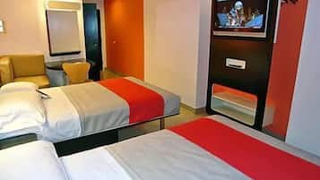 A hotel room with two beds, a TV, and a seating area with a sofa and armchairs.