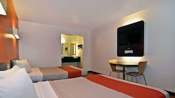 A hotel room with two beds, a desk with two chairs, a TV mounted on the wall, and a mirror.