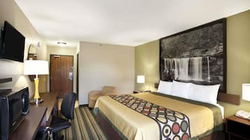 Une chambre d’hôtel comprenant un lit, un bureau avec un ordinateur, une chaise et un téléviseur.