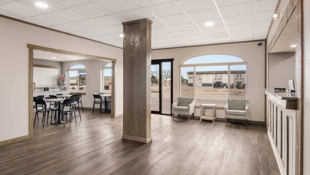 Un hall d’entrée spacieux avec un plancher en bois, un comptoir de réception et un espace salon.
