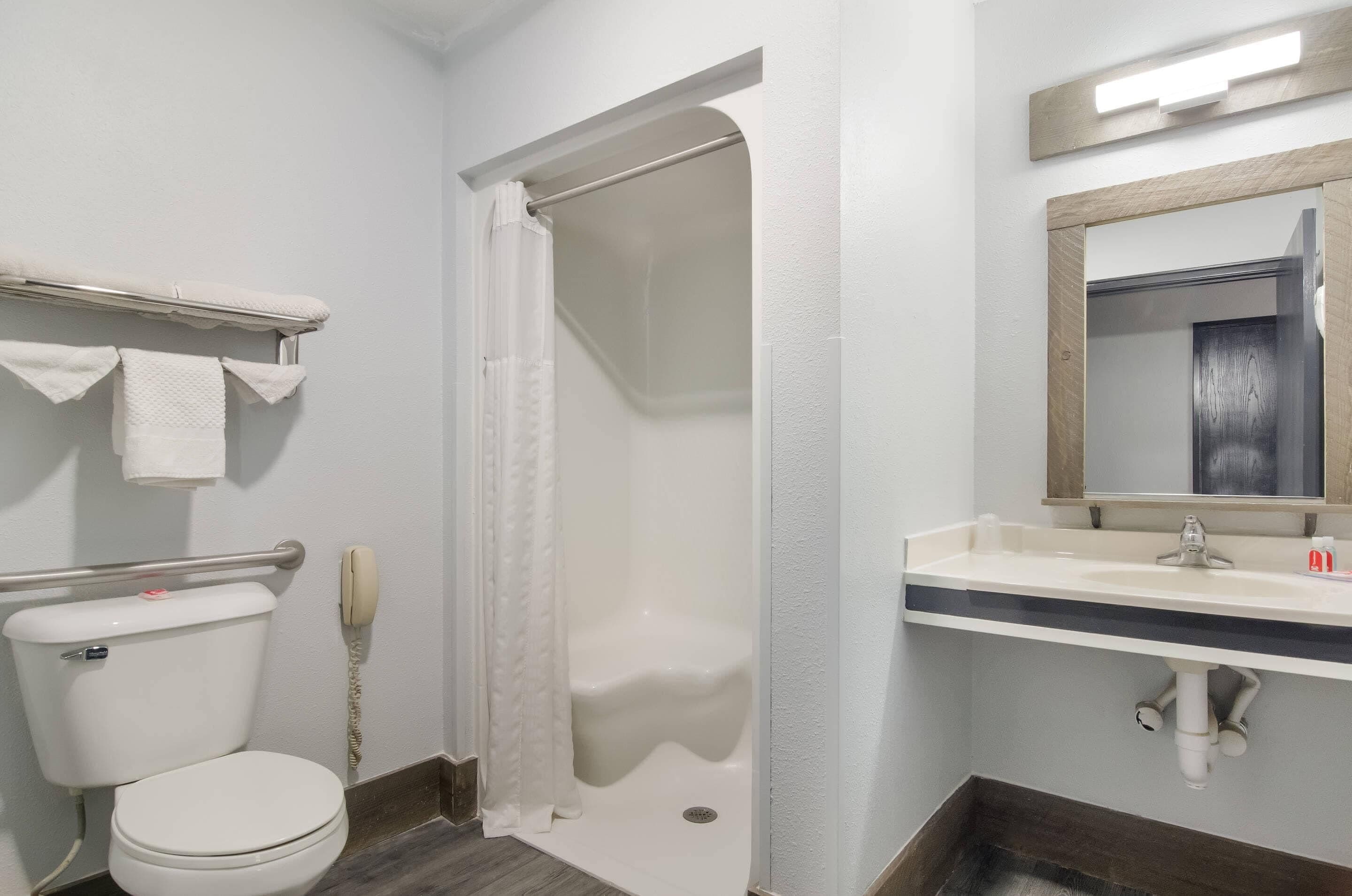 A bathroom with a toilet, shower, and sink.