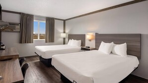 Une chambre d’hôtel avec deux lits, un bureau et une fenêtre avec des rideaux.