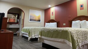 A hotel room with two beds, a desk, a mirror, and a framed picture on the wall. - Days Inn by Wyndham Bastrop (Bastrop)