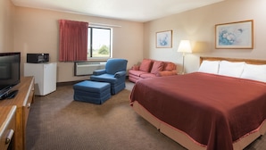 A hotel room with a bed, a desk with a television, a chair, a couch, and a window with curtains. - Super 8 by Wyndham Abilene KS (Abilene)