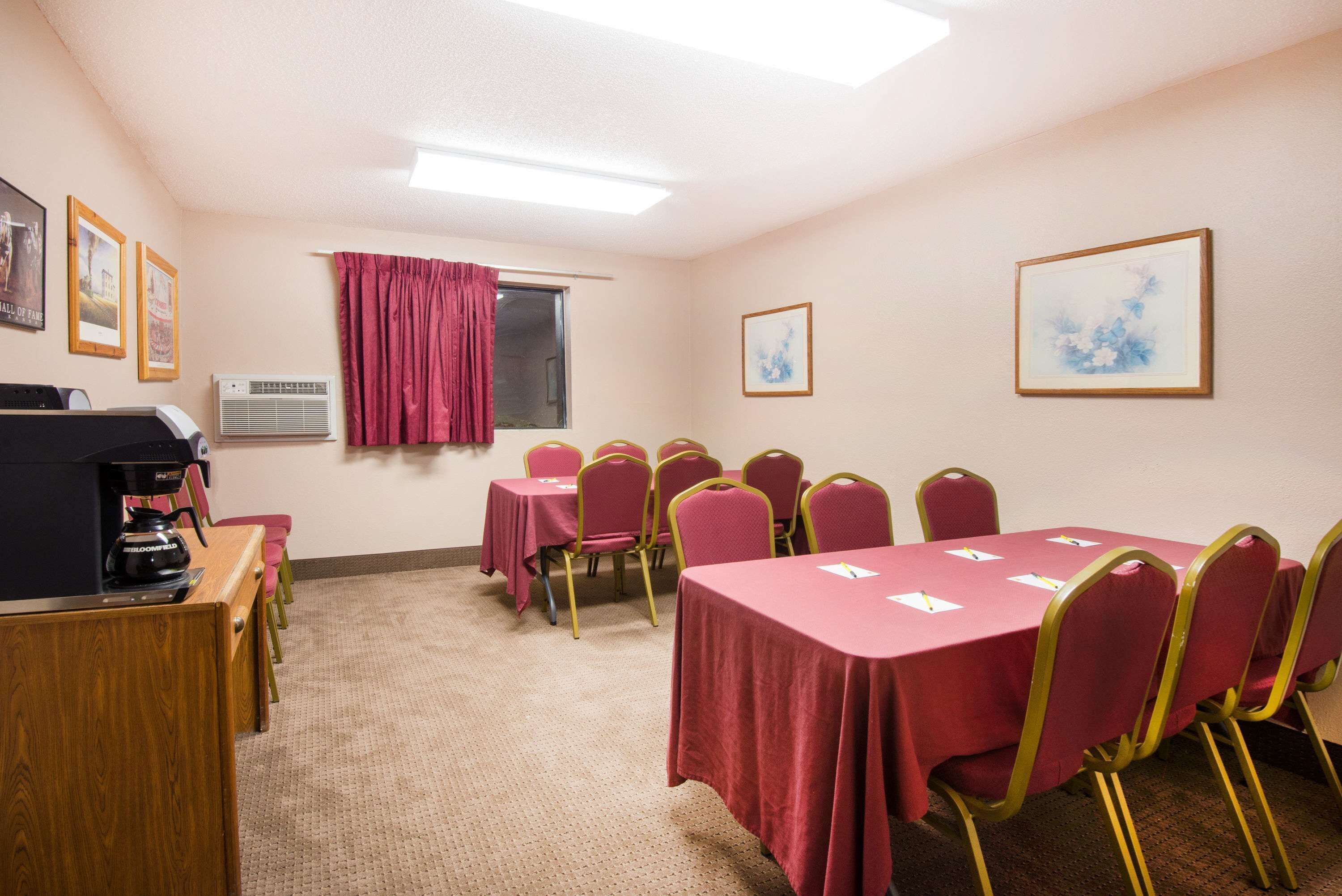 A conference room with a long table, chairs, a coffee machine, and framed pictures on the walls.