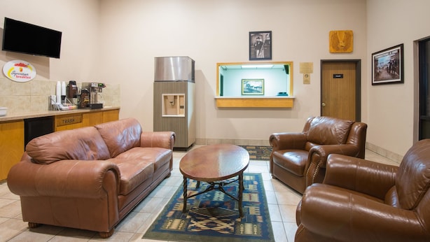 A hotel lobby with a kitchenette, leather sofas, a coffee machine, a TV, and framed pictures on the wall. - Super 8 by Wyndham Abilene KS (Abilene)