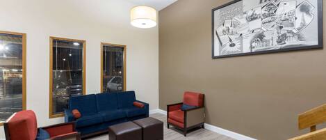 A living room with a blue sofa, two armchairs, a wooden coffee table, and a large framed picture on the wall.