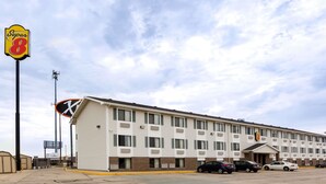 Een Super 8 motel met een rij laagbouwvormige kamers, een parkeerplaats en een heldere lucht.