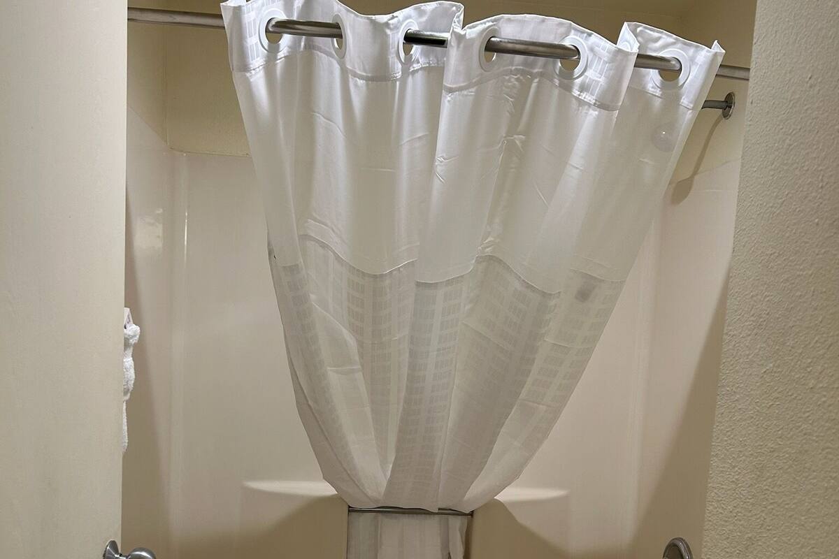 A bathroom with a bathtub, toilet, and a shower curtain.