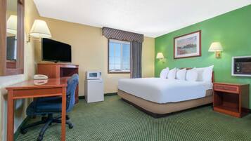 A hotel room with a bed, desk, chair, television, and a microwave.