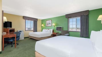 A hotel room with two beds, a desk with a computer, a chair, a TV, and a microwave.