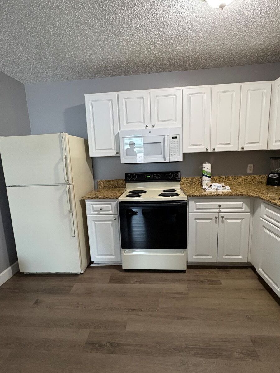 A kitchen with white cabinets, a microwave, a stove, and a refrigerator.